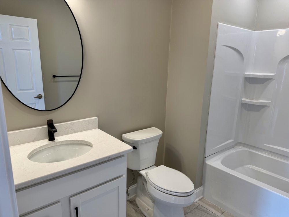 Apartment 2 bathroom vanity with round mirror.
