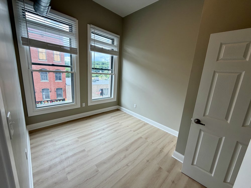 Apartment 8 bedroom with exposed brick and two windows.