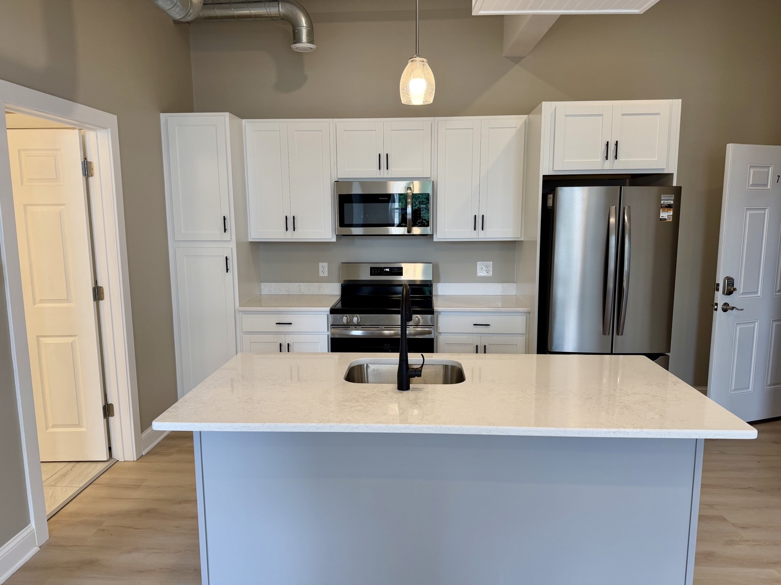 A kitchen at 355 Main Street — white shaker cabinets, stainless range and refrigerator, and a quartz-topped center island.