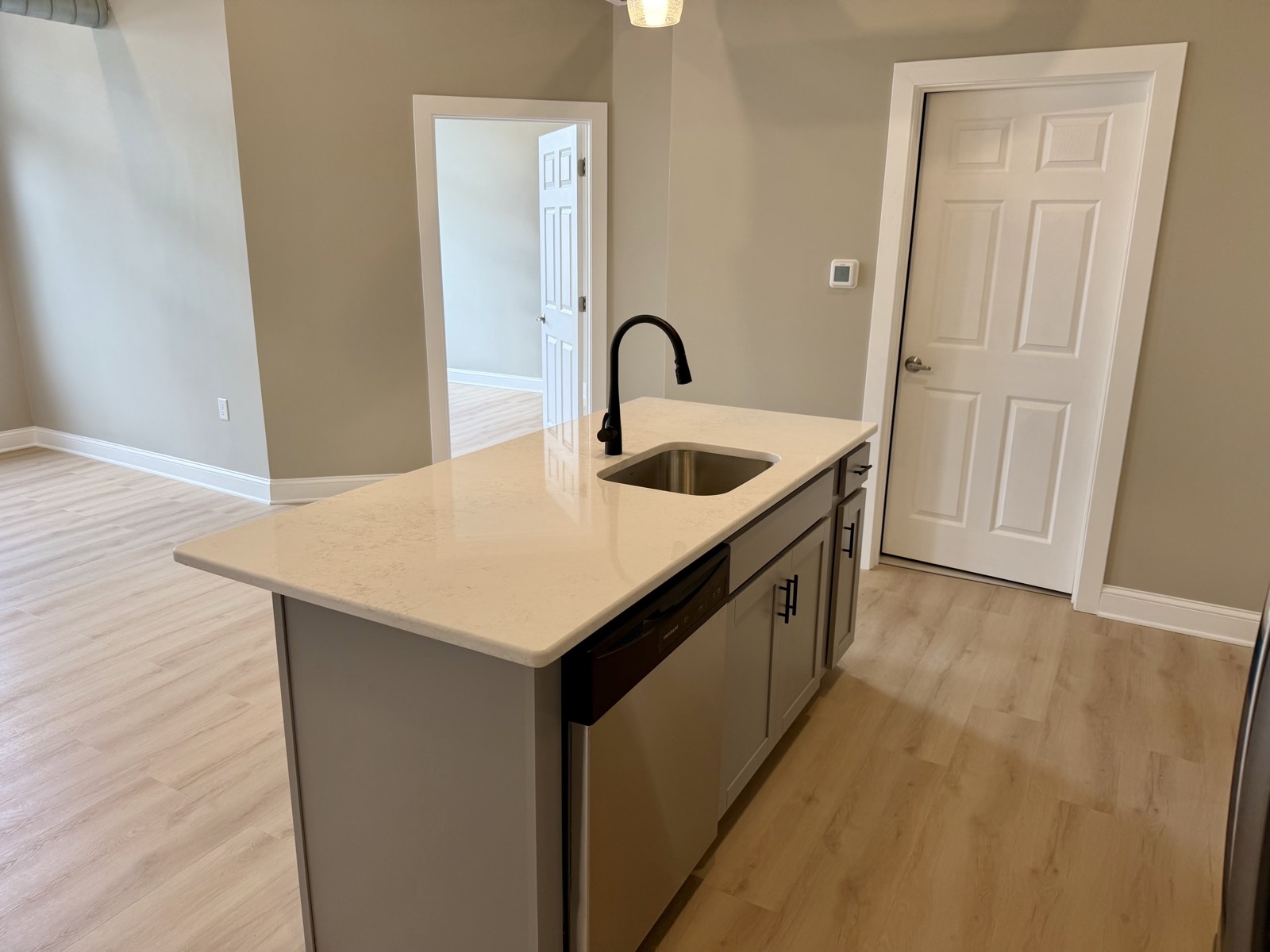 Quartz center island with undermount sink, matte black faucet, and built-in dishwasher.