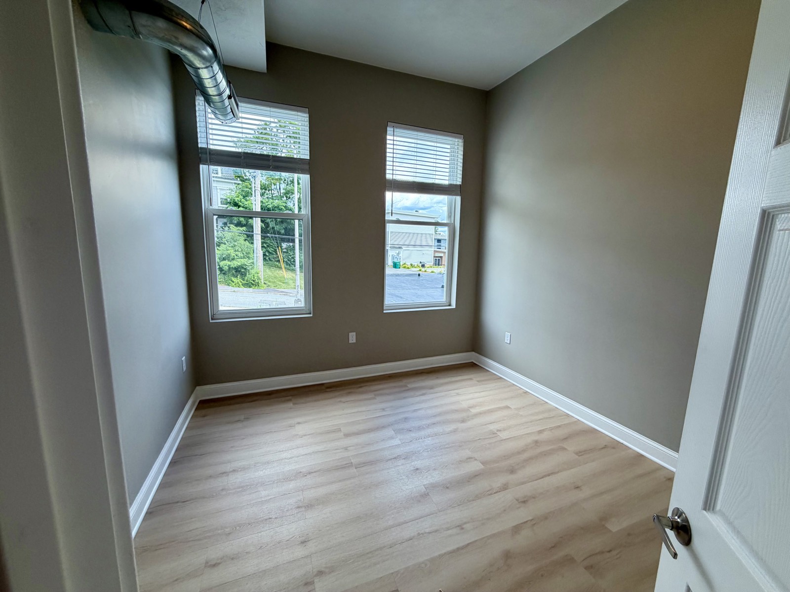 Bedroom with two large windows and wide-plank flooring.
