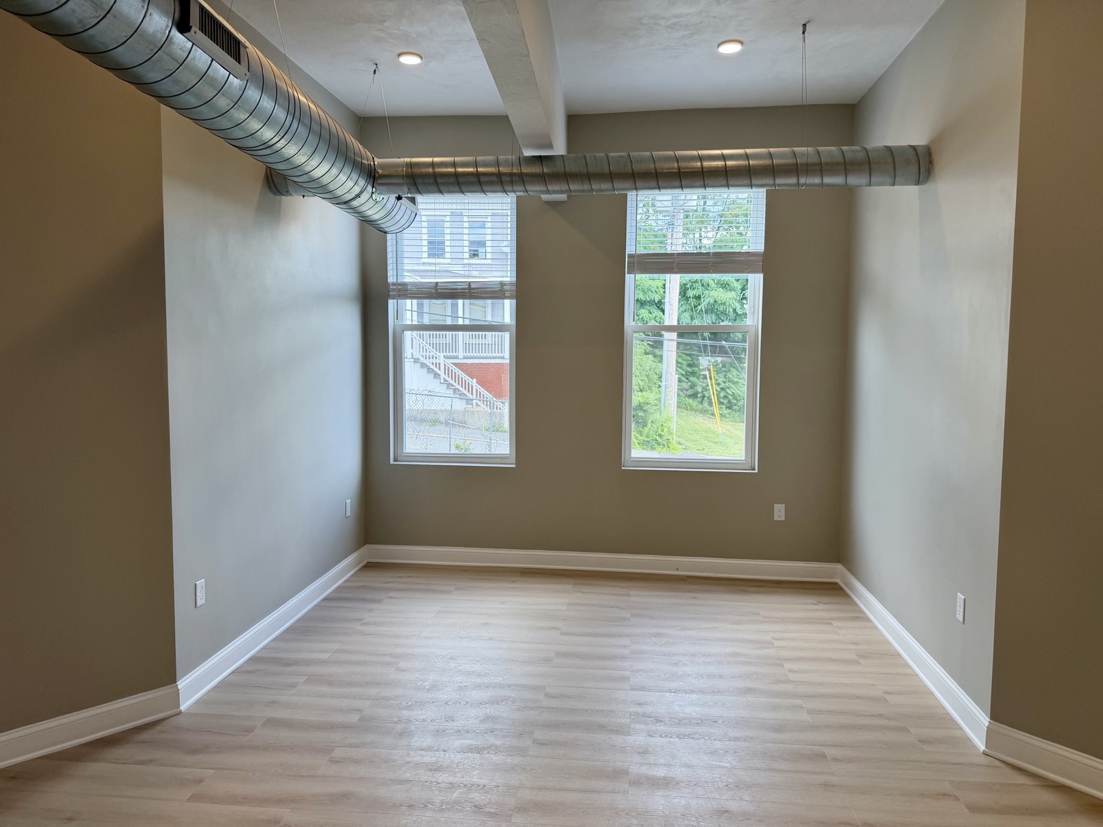 Bedroom with exposed spiral ductwork running below the ceiling.