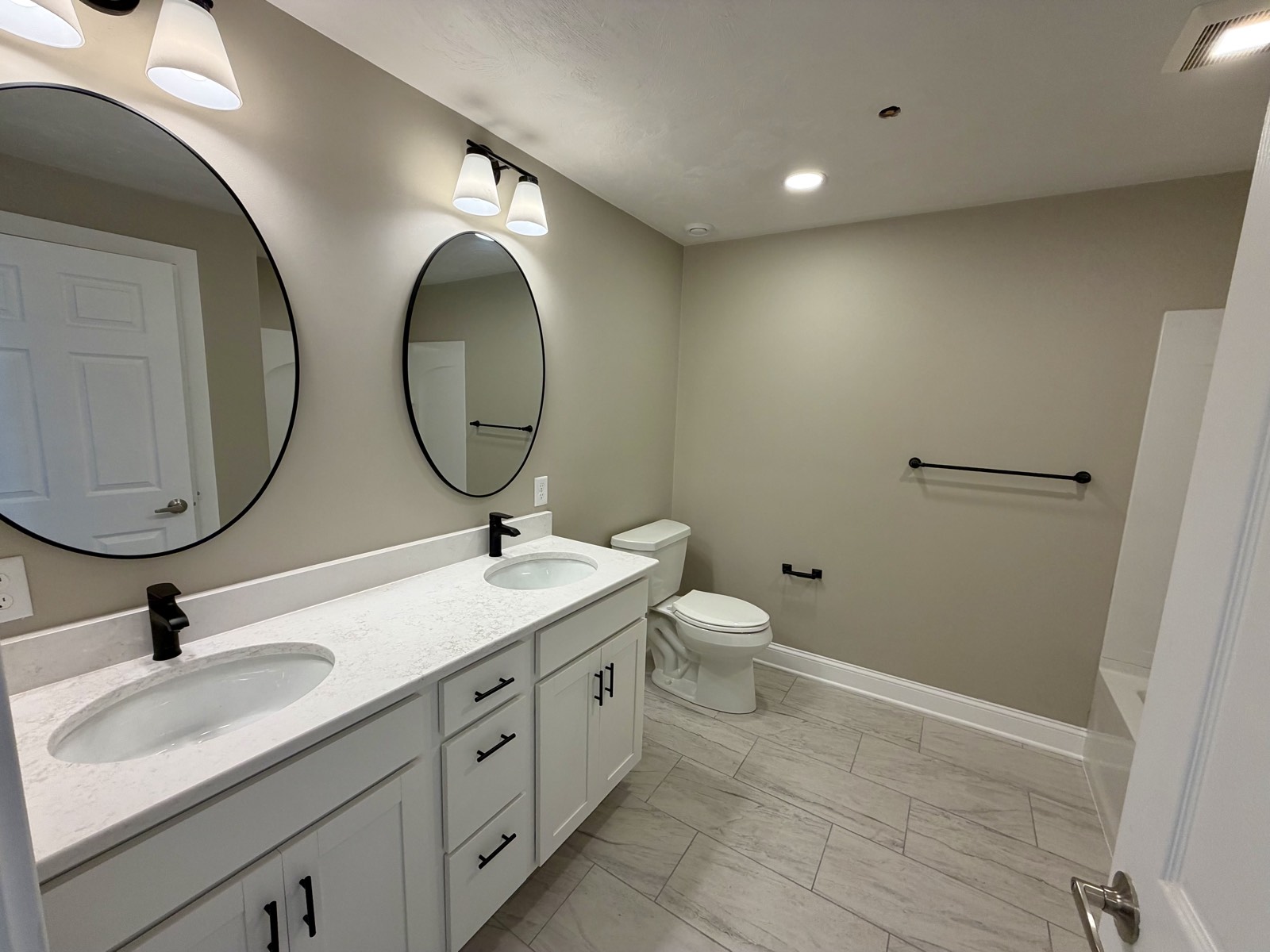 Bathroom with a double vanity, quartz top, and two round mirrors.