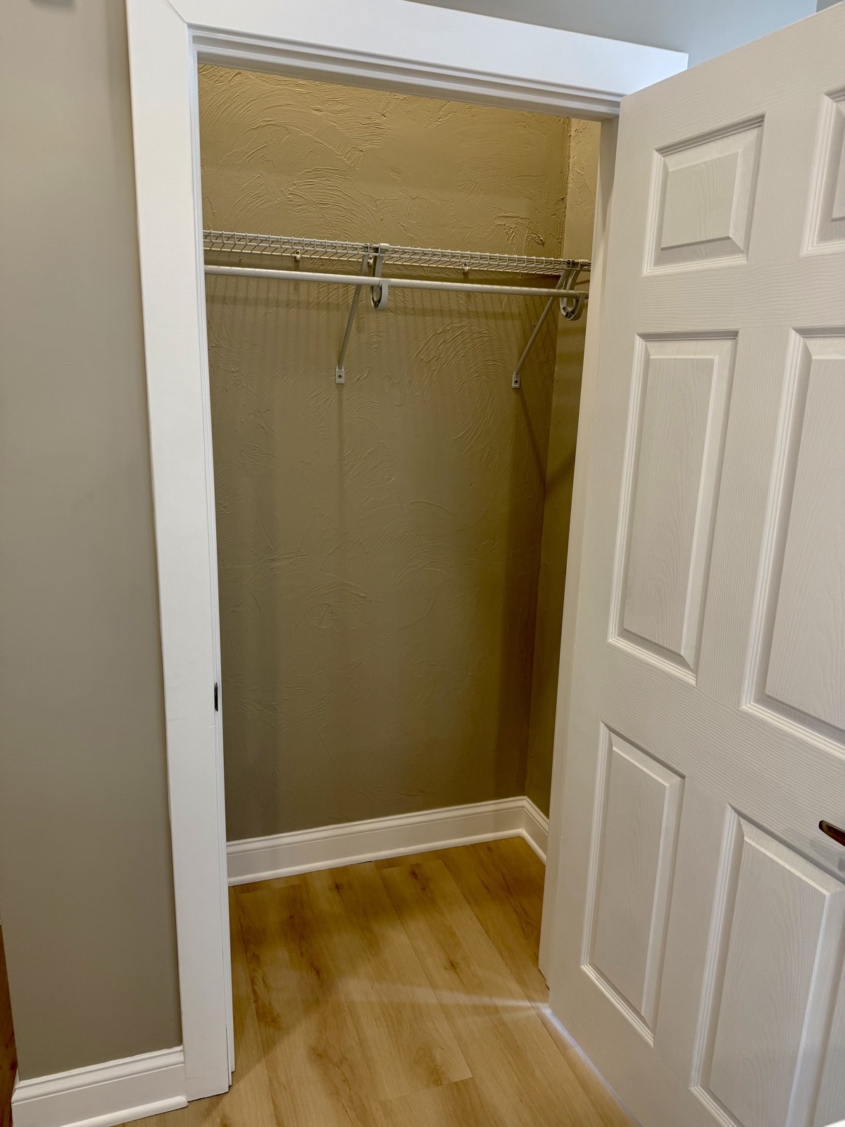 Reach-in closet with wire shelf and hanging rod.